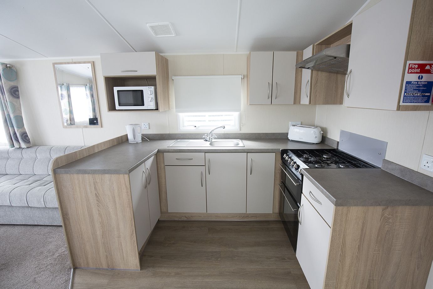 A compact kitchen with a microwave, toaster, sink, and stove.