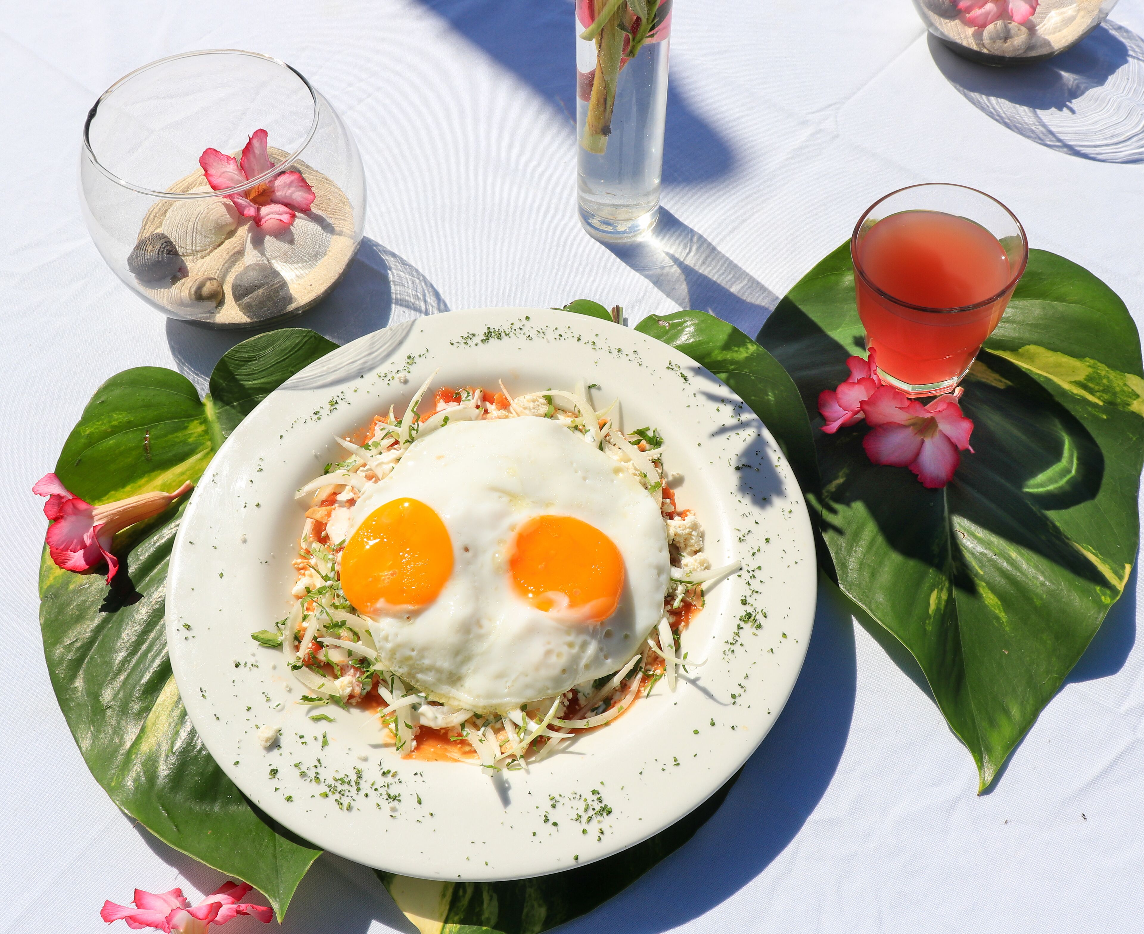 Un piatto con un pasto da colazione, un bicchiere e elementi decorativi su un tavolo.
