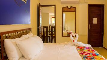 Una habitación de hotel con cama, espejo, puerta y un cuadro en la pared.