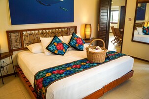 Uma cama com cabeceira de madeira, duas almofadas, um edredom colorido e uma cesta de vime ao lado.