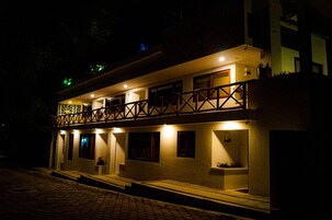 Um edifício de dois andares com varanda e várias janelas, provavelmente um hotel ou pousada.