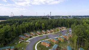 Een camping met meerdere huisjes, een parkeerplaats en een achtbaan op de achtergrond.
