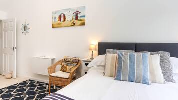 A bedroom with a bed, a chair, a nightstand, a lamp, and a painting on the wall.