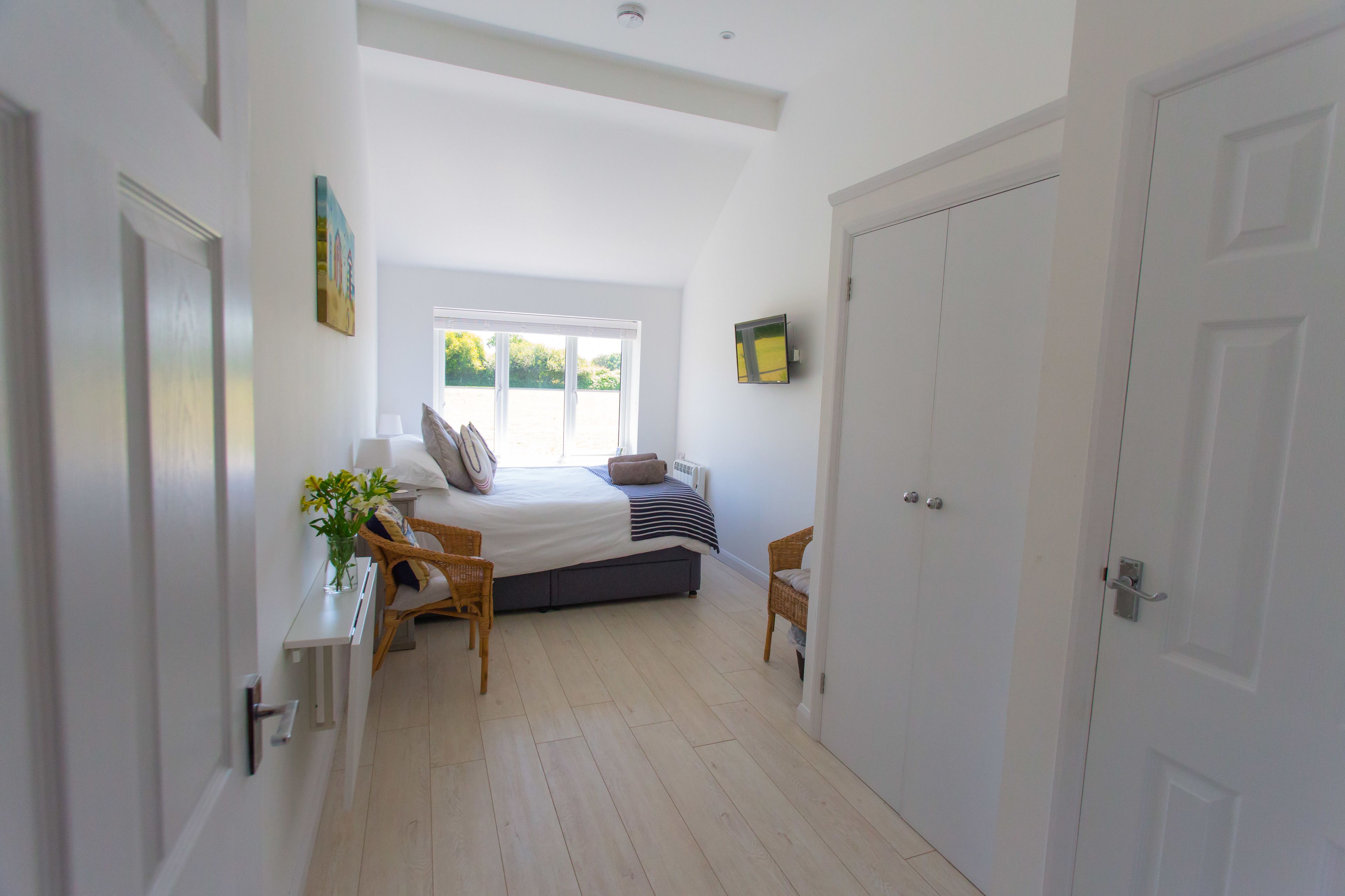 Un dormitorio con cama, mesitas de noche, ventana y puerta.