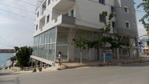 A multi-story building with a glass facade, a staircase leading to the entrance, and a view of the sea. - Belvedere Apartaments 2 (Sarandë)