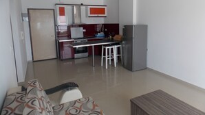 A compact kitchen with a stove, refrigerator, and bar stools. - Belvedere Apartaments 2 (Sarandë)