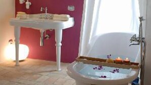 Un baño con una bañera blanca, un lavamanos blanco y un espejo en la pared.