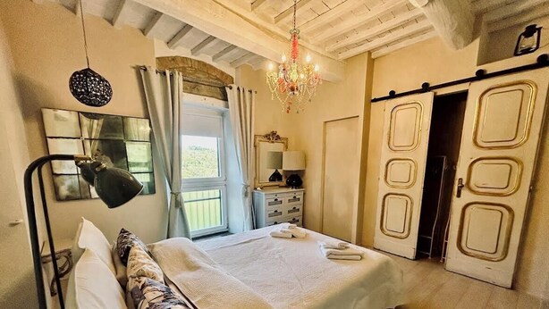 Un dormitorio con cama, escritorio, silla, candelabro y armario.