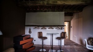 Un interior moderno con una escalera, dos taburetes de bar, una mesa y un lámpara colgante.