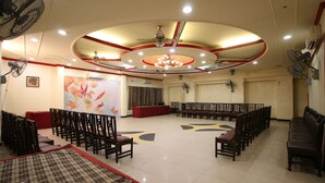 A spacious hall with rows of chairs, a ceiling fan, and a chandelier. - Motel Divine International (Roorkee)