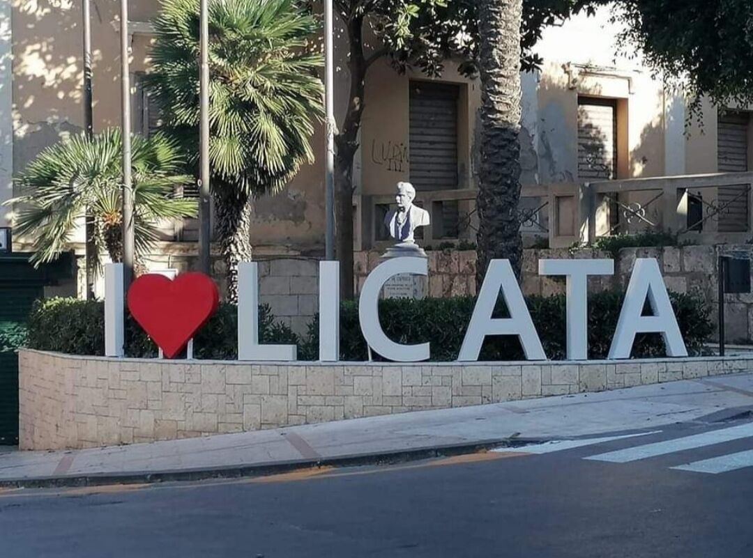 Un cartello con la scritta 'I ♥ LICATA' e una statua a busto.