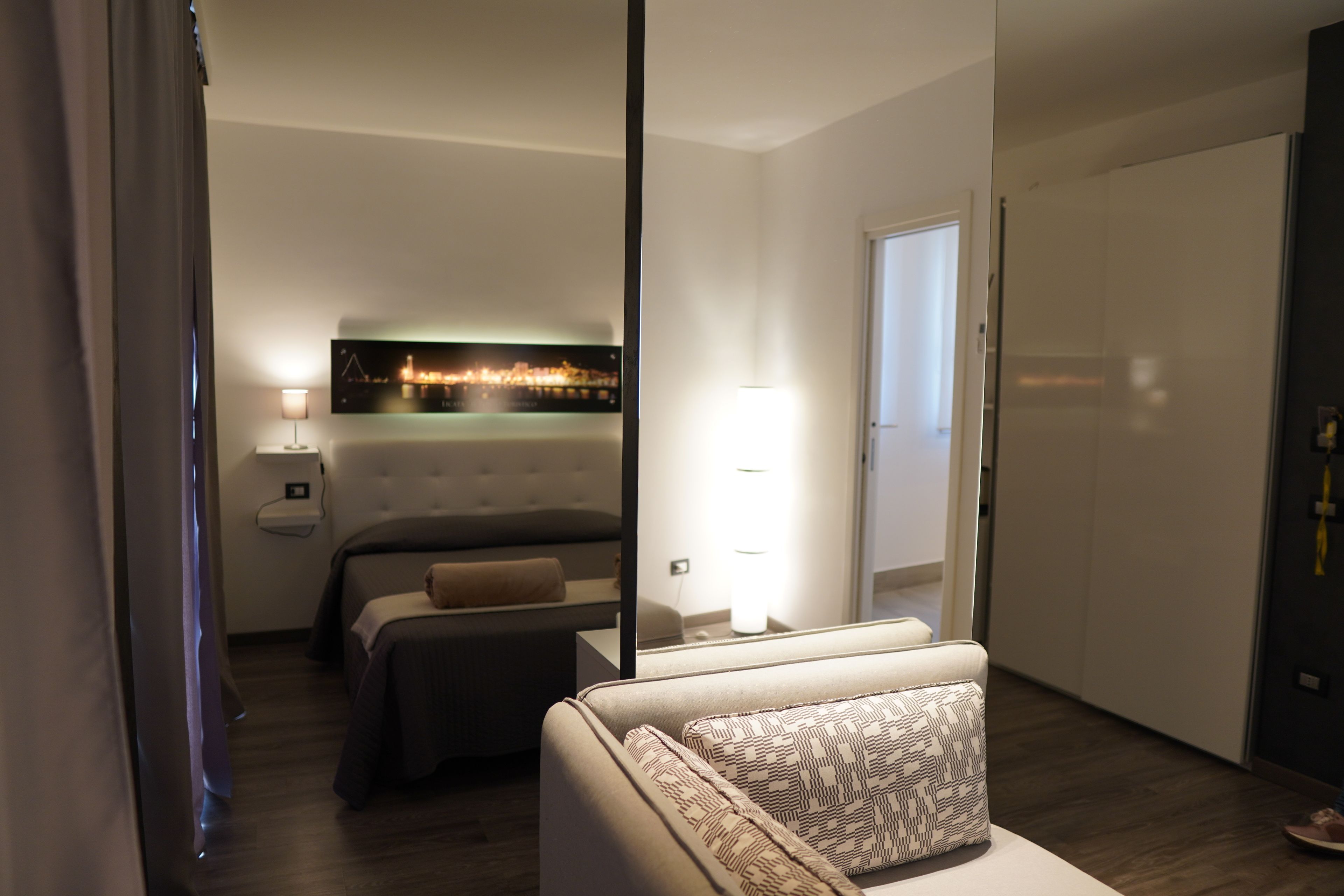 Una camera d'albergo moderna con un letto, un divano, un comodino e una TV a parete.