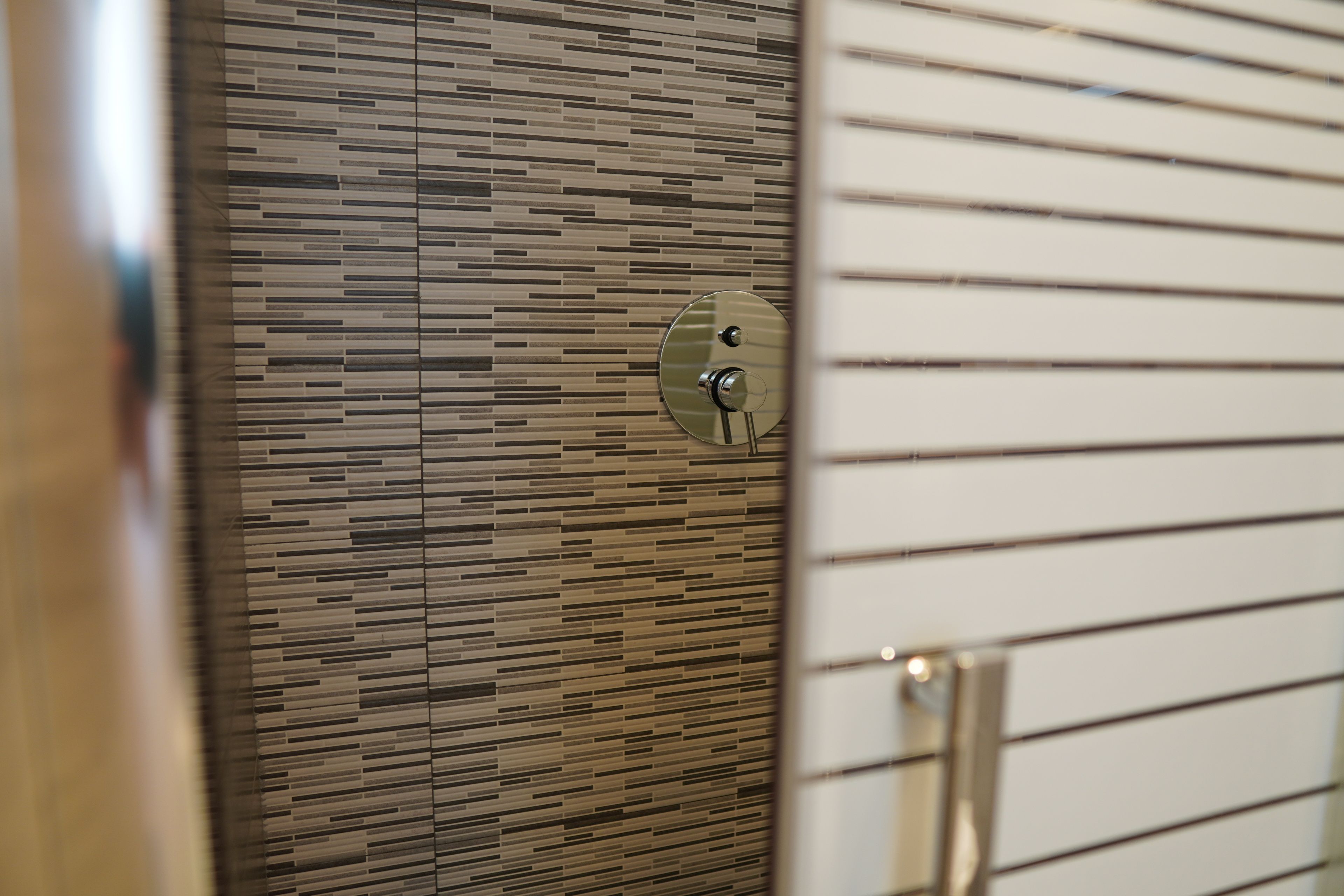 Une salle de bain moderne avec un mur carrelé et un robinet métallique.