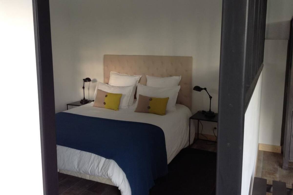 A neatly made bed with a blue and white duvet, multiple pillows, and bedside lamps.