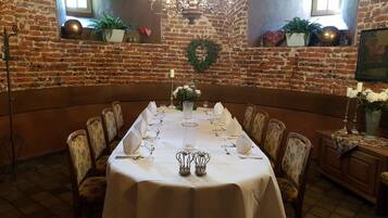 A long dining table set for a meal in a room with brick walls and a chandelier.