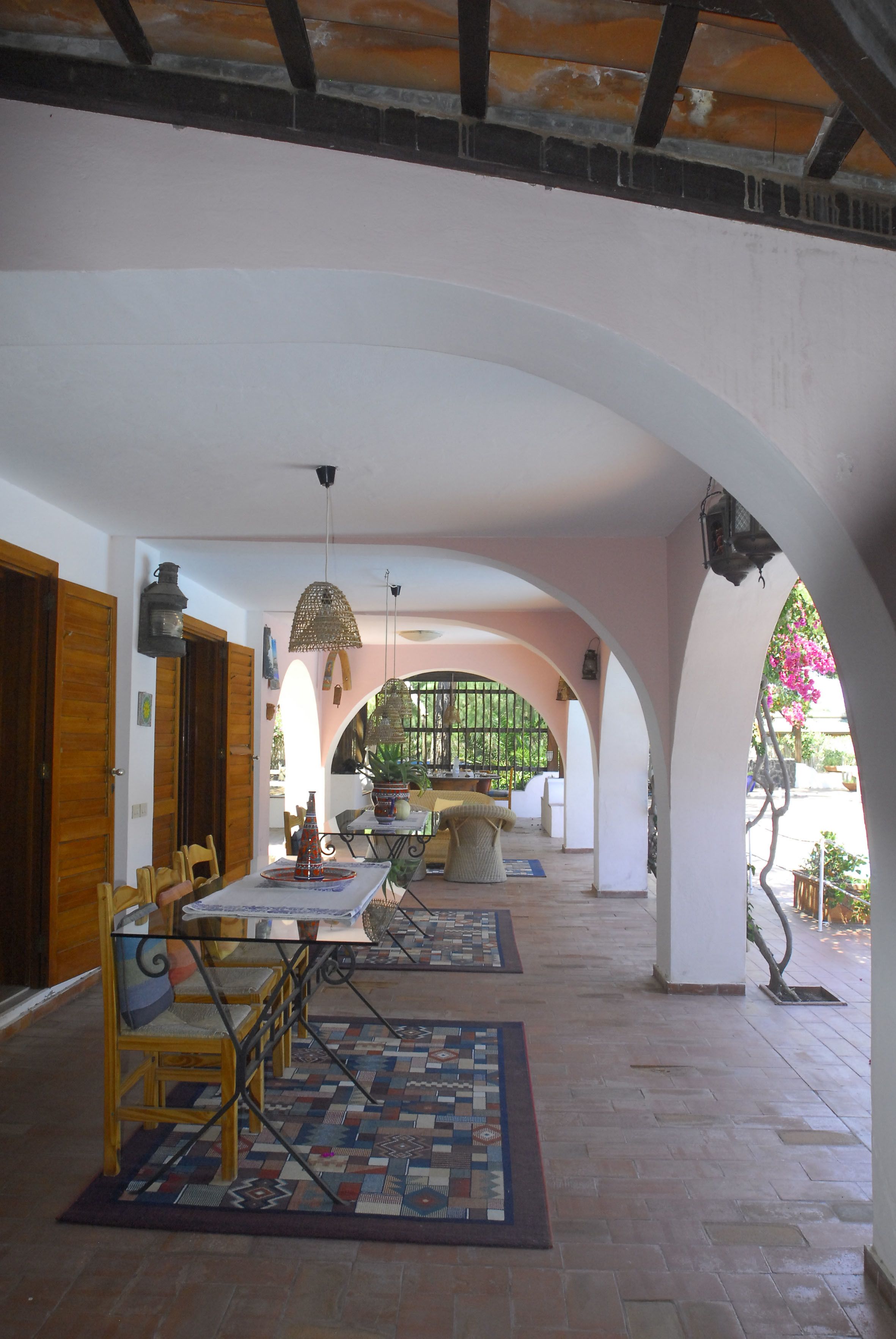 An interior with a dining area, wooden doors, and a view through an archway.