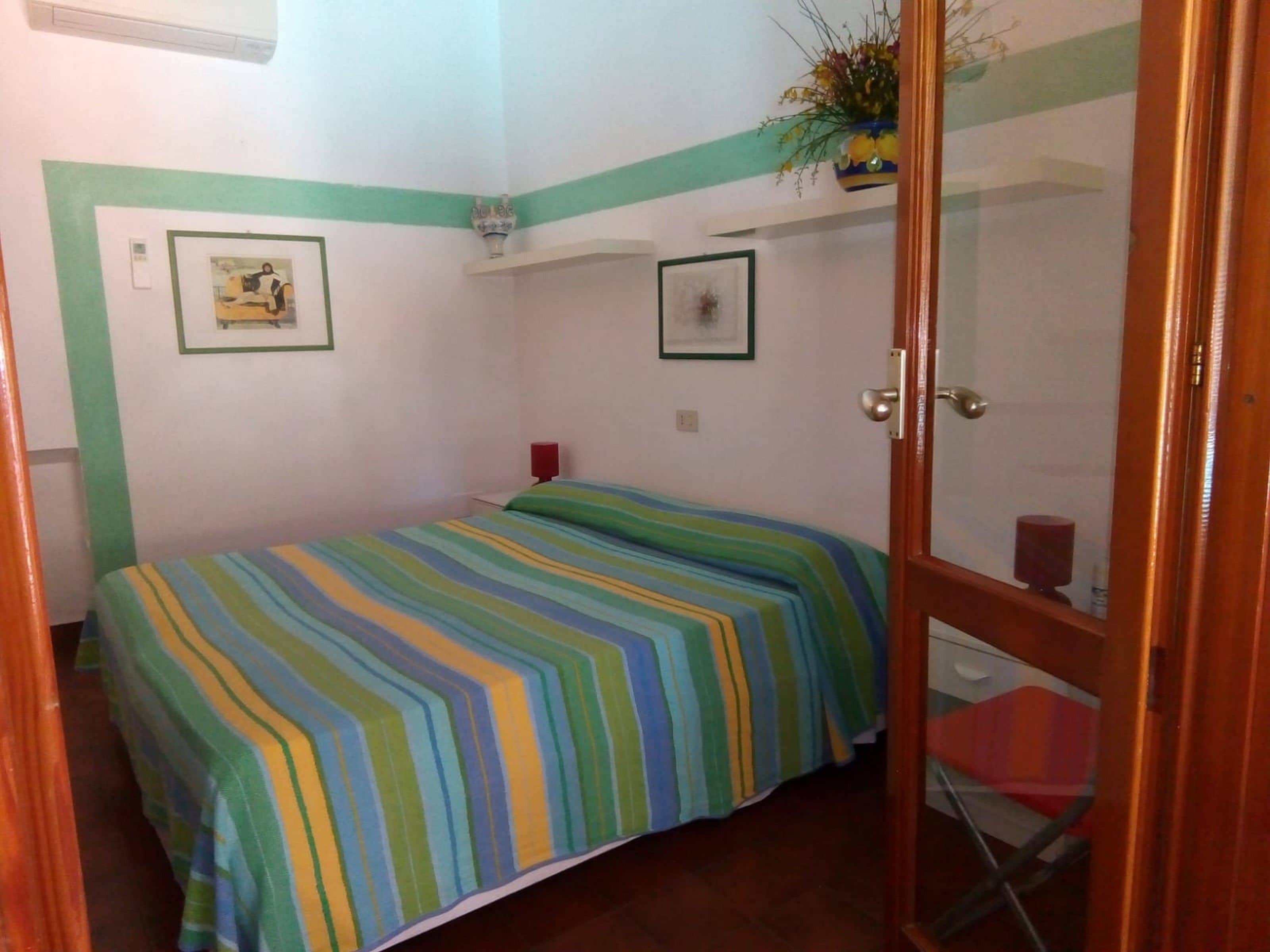 Une petite chambre à coucher, bien rangée, avec un lit, une petite table et une chaise.