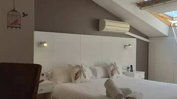 A bedroom with a skylight, white bedding, and decorative pillows.