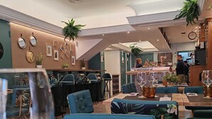 Un interior de restaurante moderno con asientos tapizados en azul, una zona de bar y elementos decorativos en la pared.