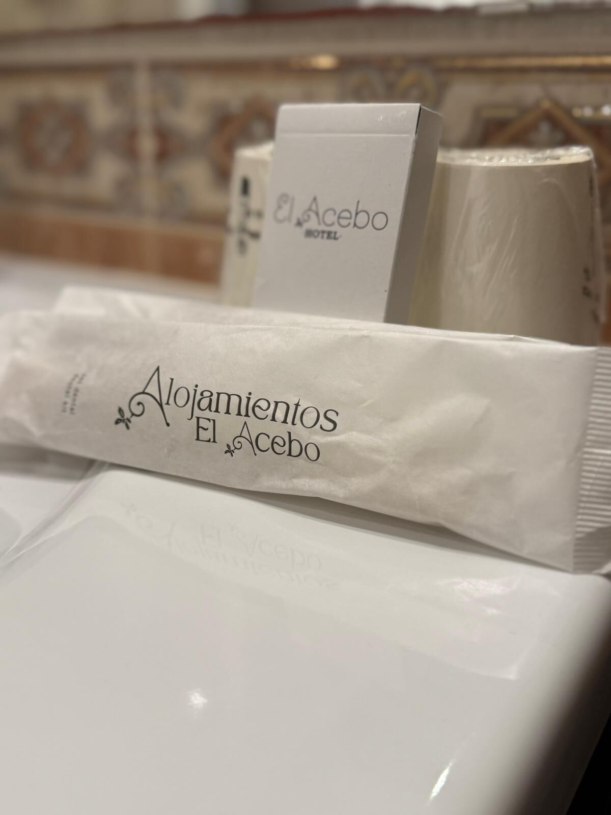 A hotel room with a tiled backsplash and a white package labeled "Alojamientos El Acebo".