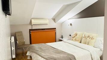 Una camera da letto con un letto, una sedia, un comodino, un condizionatore d'aria e una TV a parete.
