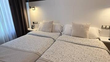 A double bed with a patterned bedspread, a dark headboard, and bedside lamps.