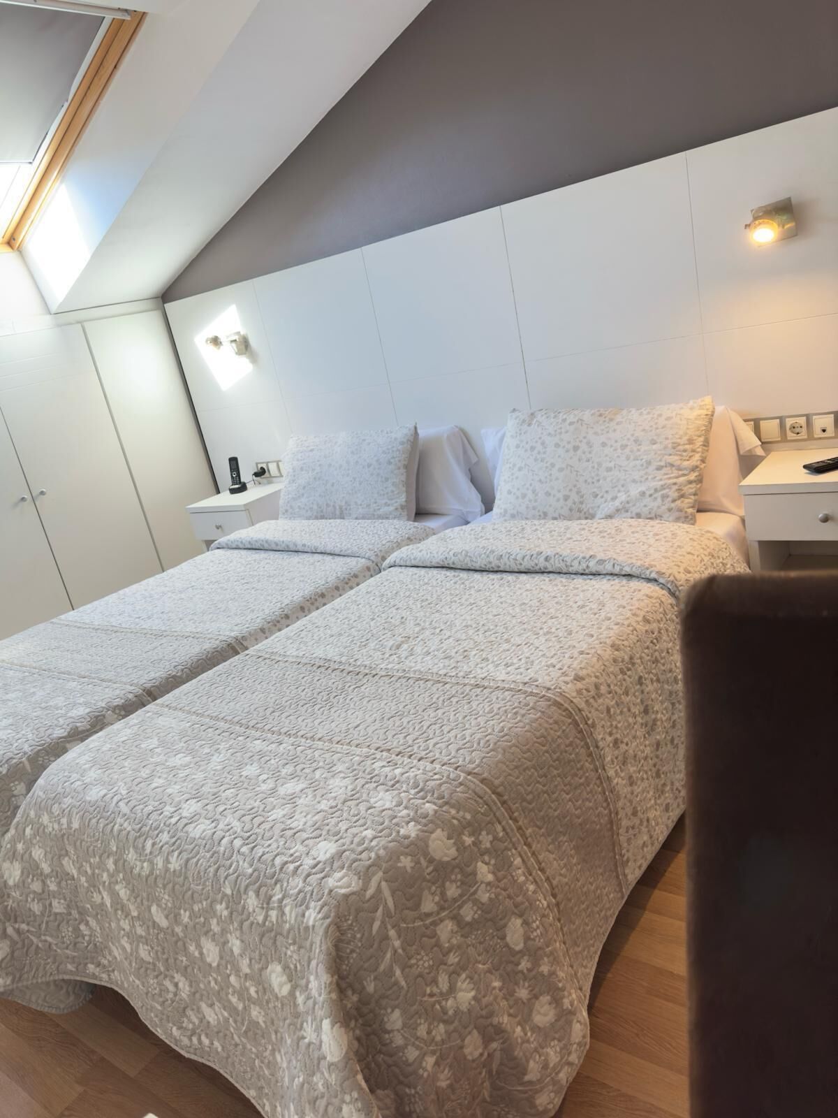 A modern bedroom with a large bed, bedside tables, and a skylight.
