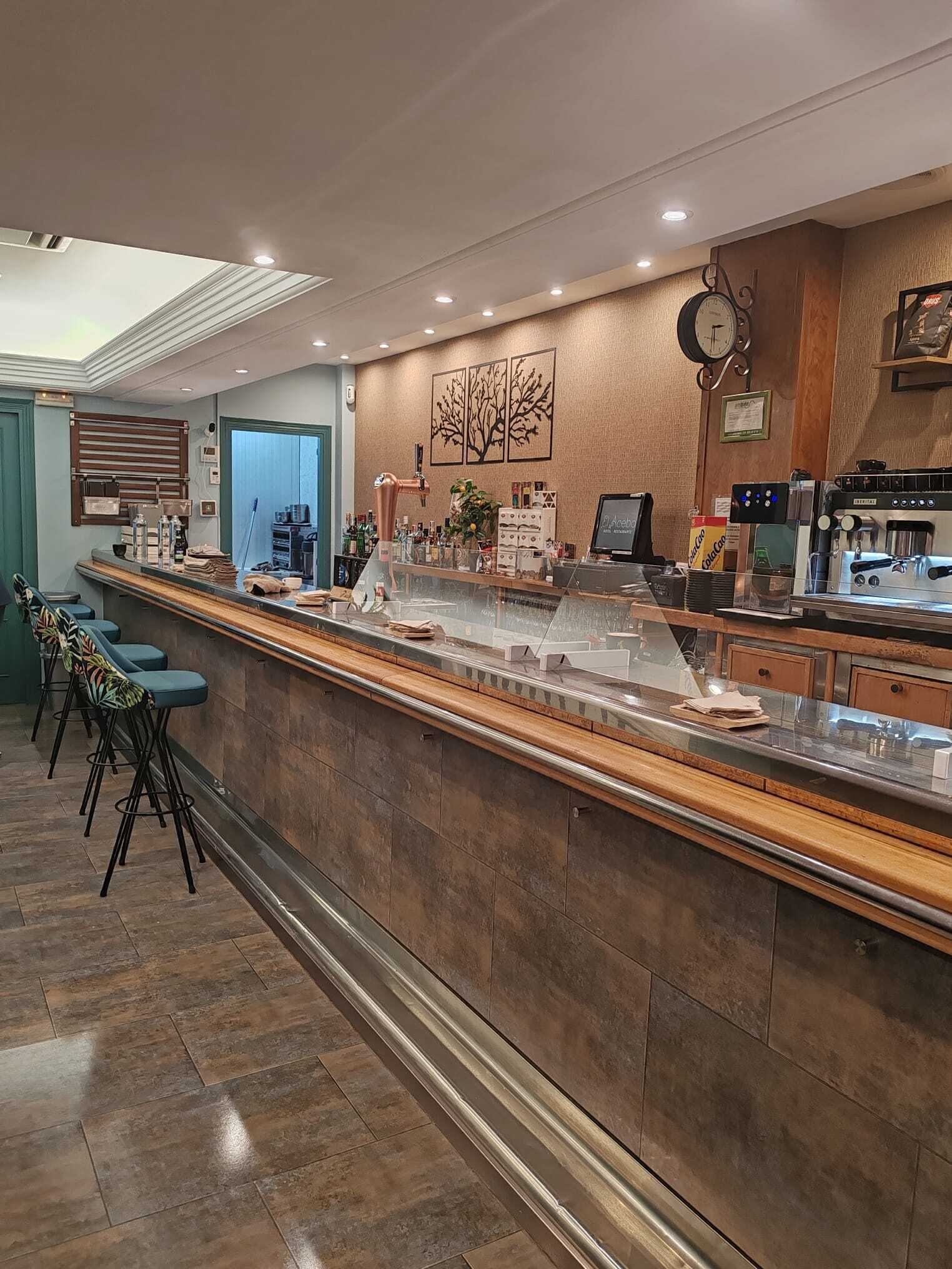 A modern bar area with a long counter, stools, and a coffee machine.