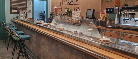A modern bar area with a long counter, stools, and a coffee machine.