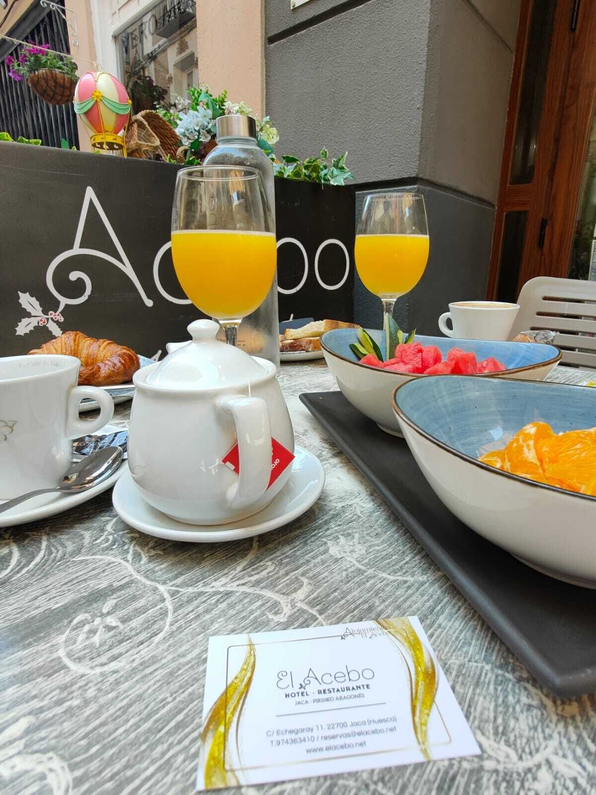 Colazione servita con croissant, succo d'arancia e teiera su un tavolo con il menu dell'Hotel Restaurante El Acebo.