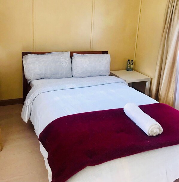 A hotel room with a bed, a nightstand, and a red blanket.