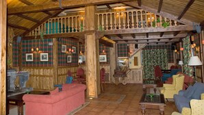 Un acogedor interior de cabaña con vigas de madera, decoración a cuadros y asientos cómodos.