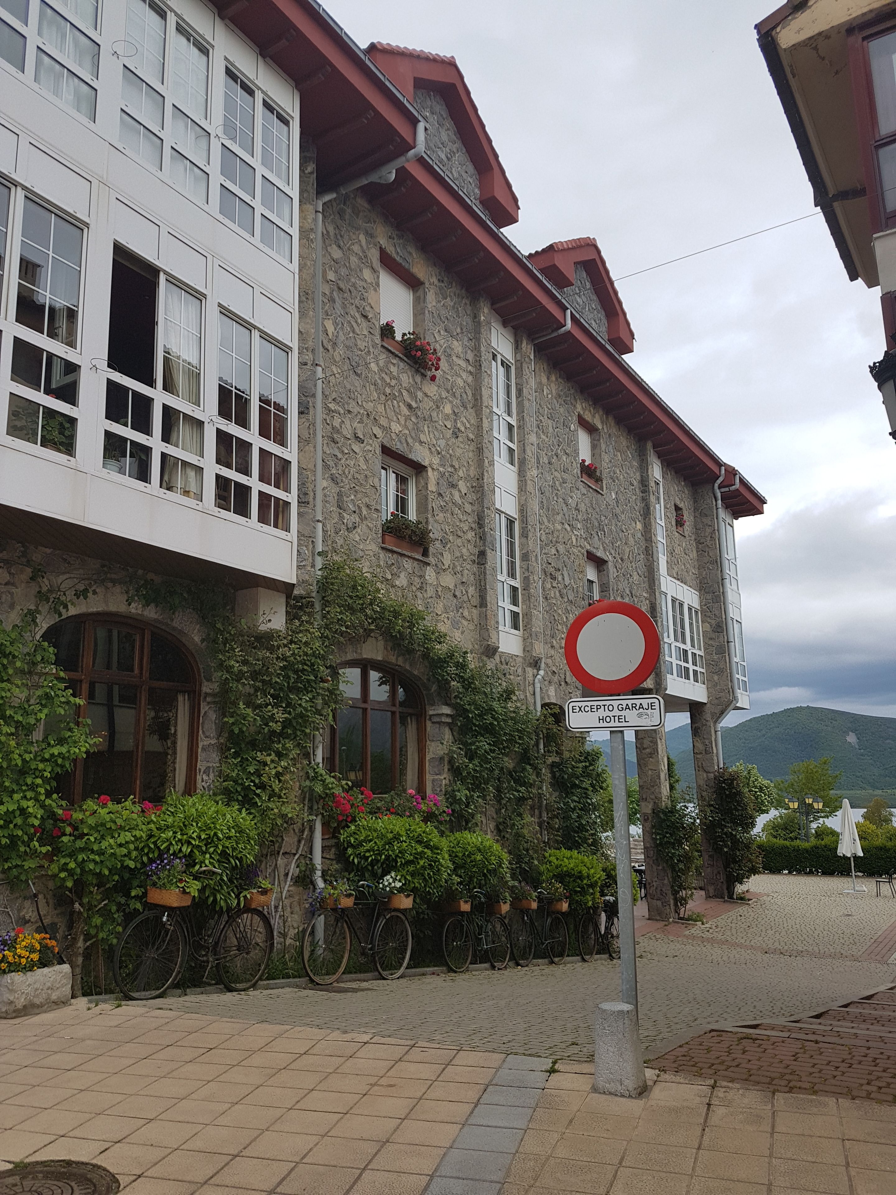 Un edificio de piedra con varias ventanas y balcones, un letrero que indica “EXCIPTO GARAGE HOTEL” y bicicletas estacionadas afuera.