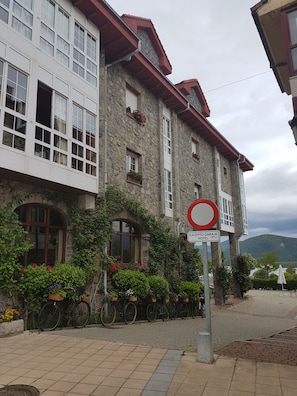 A stone building with multiple windows and balconies, a sign indicating an "EXCIPTO GARAGE HOTEL," and bicycles parked outside. - Hotel Presa (Riano)