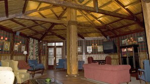 Una habitación amplia con vigas de madera, papel tapiz escocés y varias zonas de estar, incluyendo sofás y sillones.