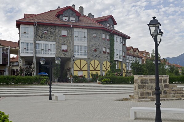 Un edificio histórico de piedra con múltiples ventanas y un techo de tejas rojas.
