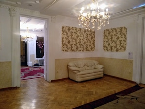 Una habitación con piso de madera en patrón espiga, un sofá color beige y un candelabro.