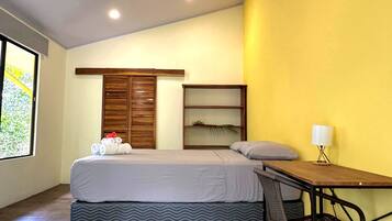 Une chambre à coucher comprenant un lit, un bureau, une chaise, un ventilateur de plafond et une fenêtre.