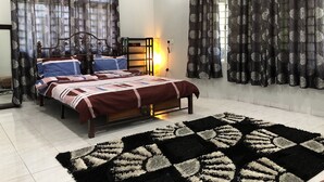 Quarto com cama, cortinas, mesa de cabeceira e tapete.