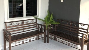 Dois bancos de madeira com detalhes metálicos elaborados, colocados em frente a uma janela com molduras brancas.