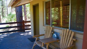 A wooden deck with a single Adirondack chair, a door, and a window with blinds. - Pendaries Village Lodge (Rociada)