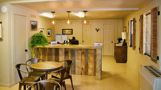 A kitchen with a wooden island, bar stools, pendant lights, and a refrigerator. - Pendaries Village Lodge (Rociada)