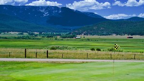 A golf course with a flagstick, a fence, and distant mountains. - Pendaries Village Lodge (Rociada)