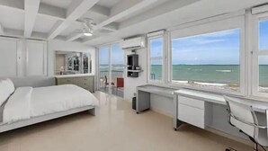 Een slaapkamer met een bed, een bureau en uitzicht op zee.