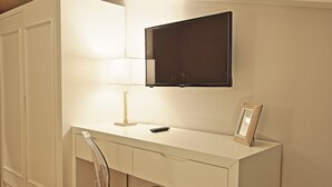 A modern bedroom with a white desk, a mounted TV, a bedside lamp, and a clear chair. - Bergamo Inn (Bergamo)