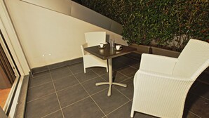 A patio area with a table and two chairs, a potted plant, and a wall with greenery. - Bergamo Inn (Bergamo)
