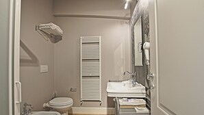 A compact bathroom with a toilet, bidet, sink, towel rack, and a mirror with a hairdryer. - Bergamo Inn (Bergamo)