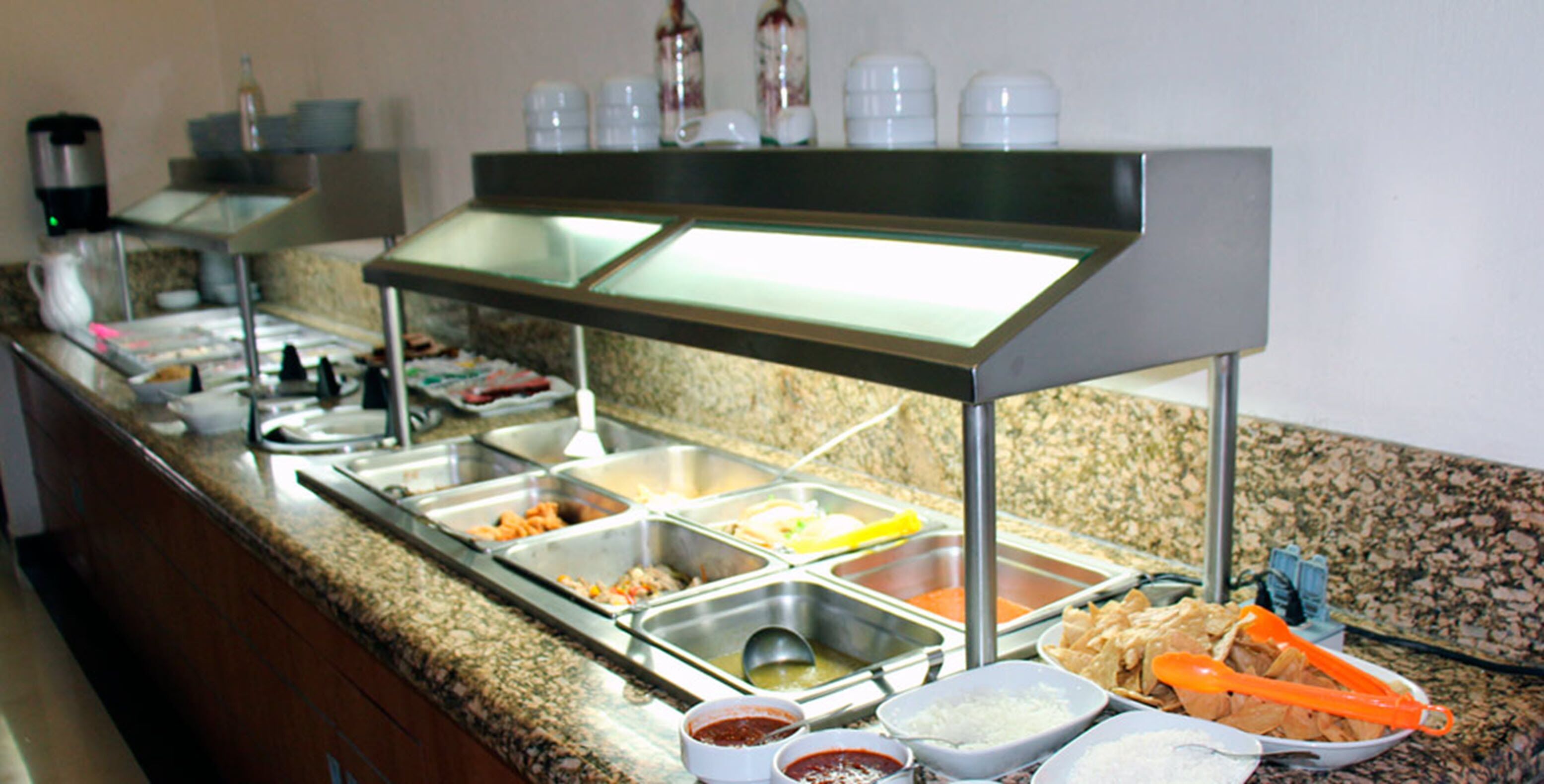 A buffet setup with various food stations and condiments.