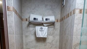 Un baño con inodoro, cabina de ducha de vidrio y un toallero con dos toallas.