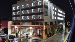 Un hôtel à plusieurs étages, doté de fenêtres illuminées et d’une entrée au niveau du sol.